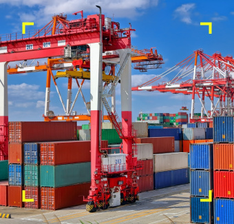 Gru industriale rossa ed enormi container colorati impilati in un porto commerciale.